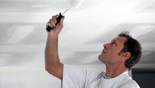 Man painting a drywall ceiling