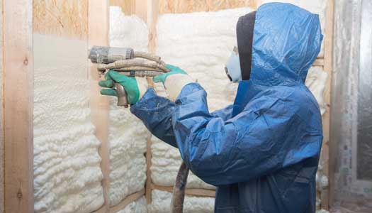 Masked worker applying spray insulation